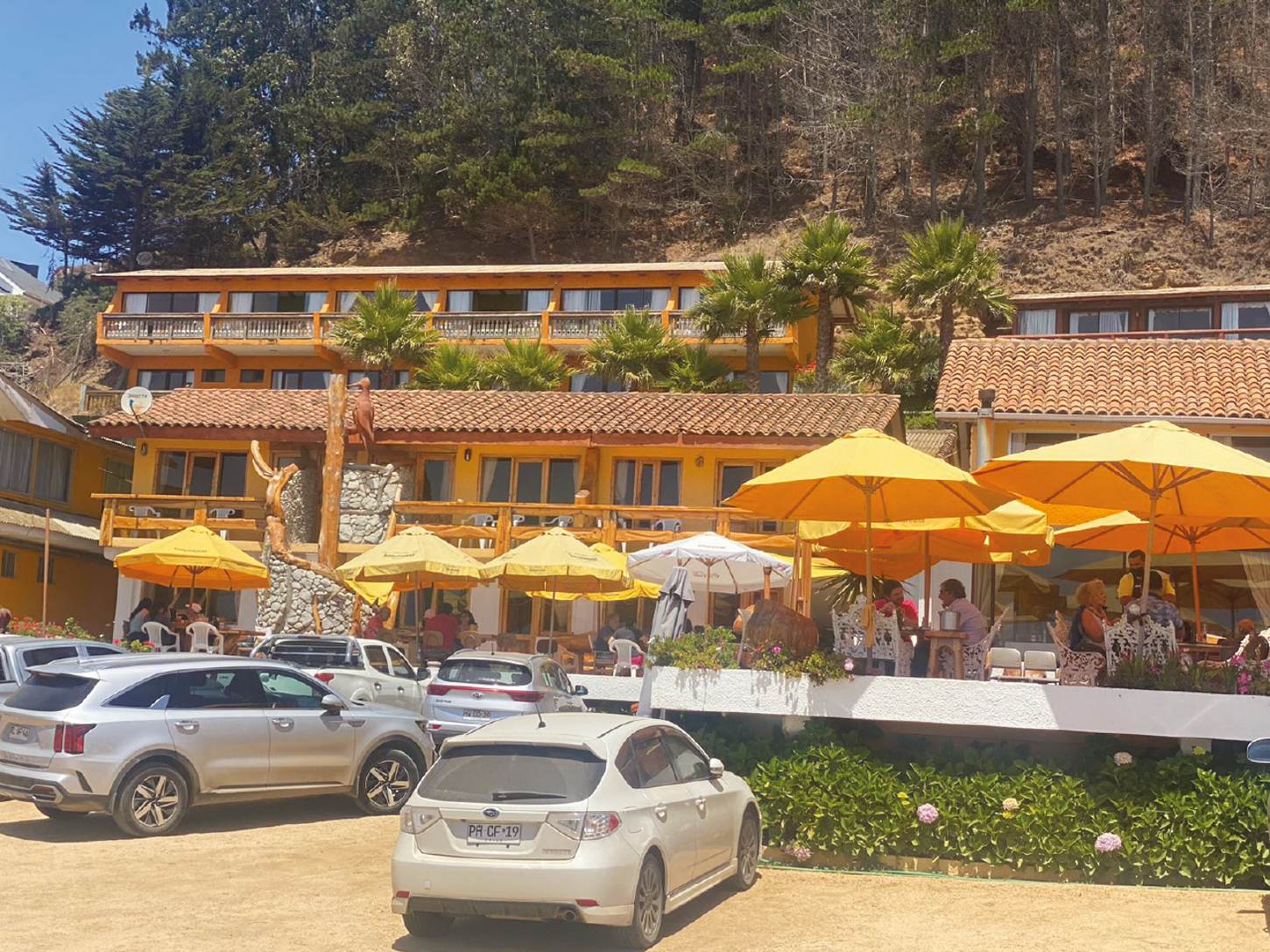 Hostería Donde Gilberto sobre la ladera, con terrazas y quitasoles frente al mar