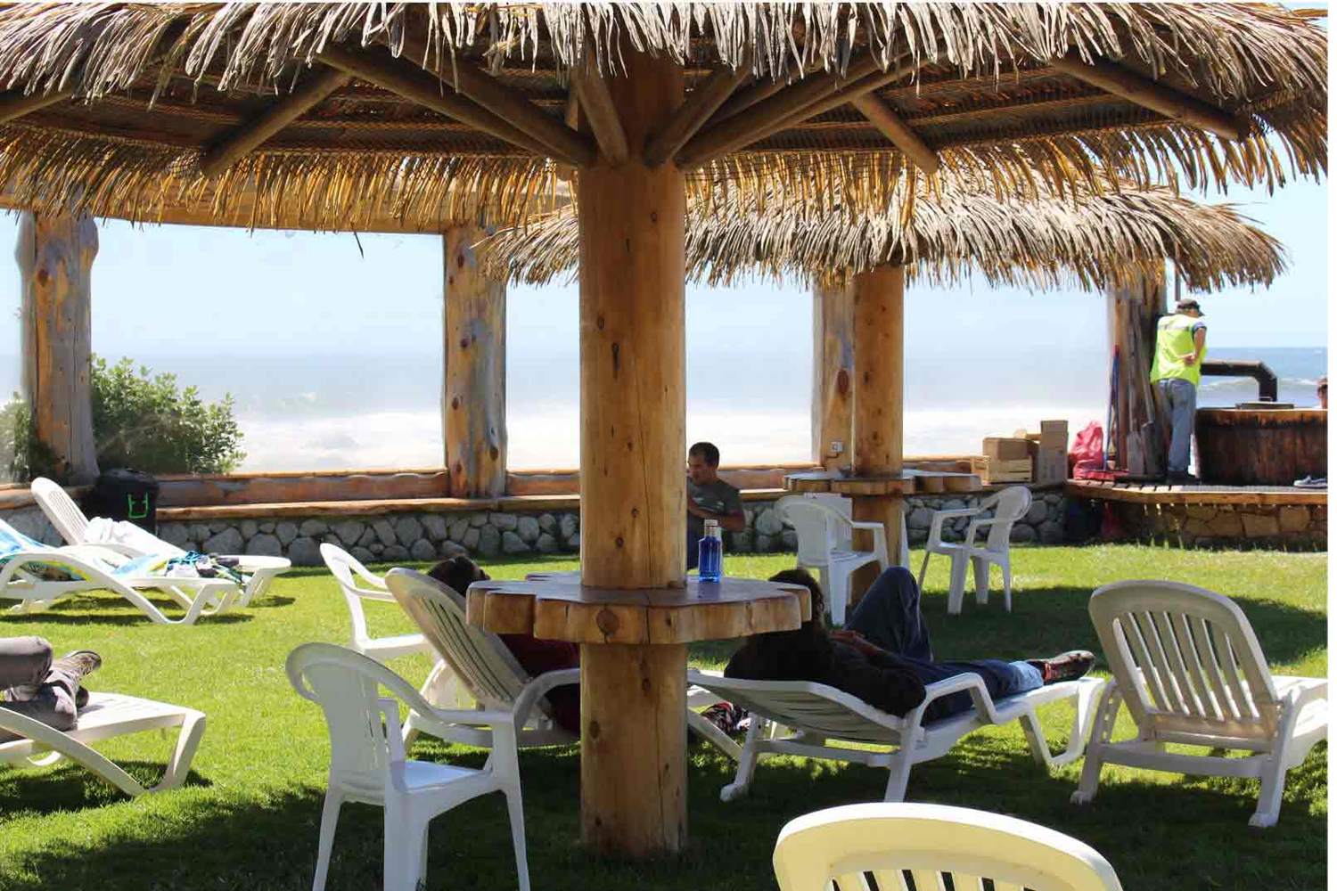 Quincho de madera y reposeras frente al mar