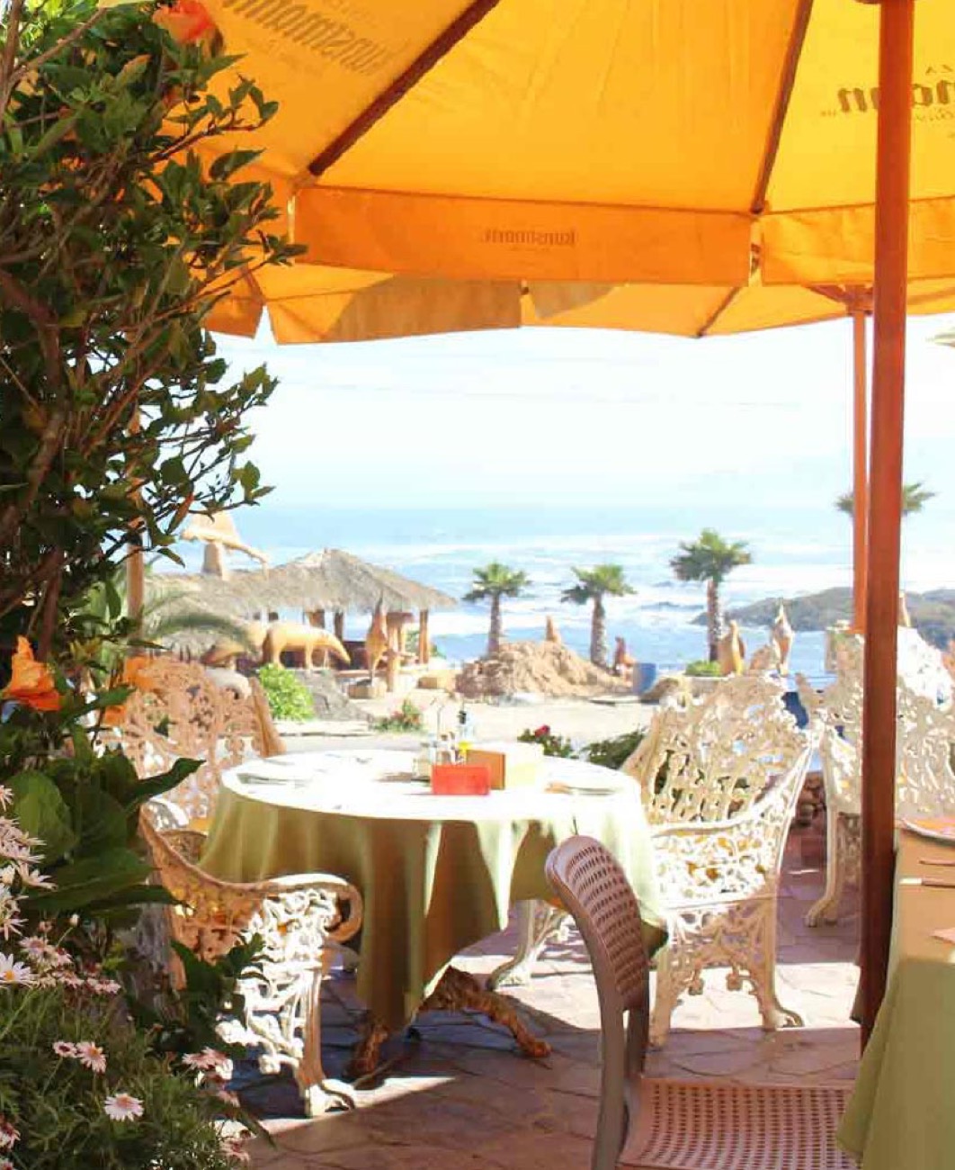 Mesa del restaurante bajo quitasol naranjo con vista al mar