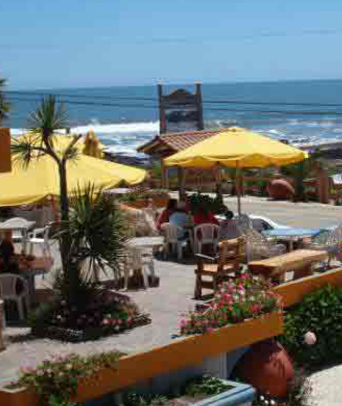 Cabaña Hostería con terrazas y quitasoles amarillos frente al mar